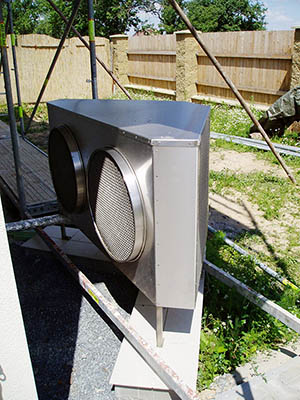Venkovní jednotka tepelného čerpadla systému vzduch-voda umístěná před objektem.